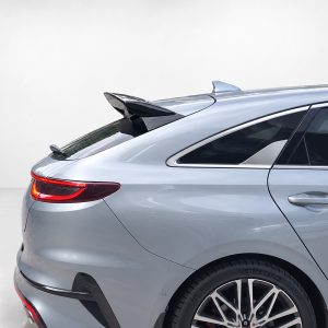 Rear quarter view of a silver luxury sedan with a small trunk spoiler and red taillight in a studio setting