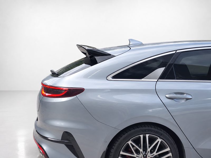 Rear quarter view of a silver luxury sedan with a small trunk spoiler and red taillight in a studio setting