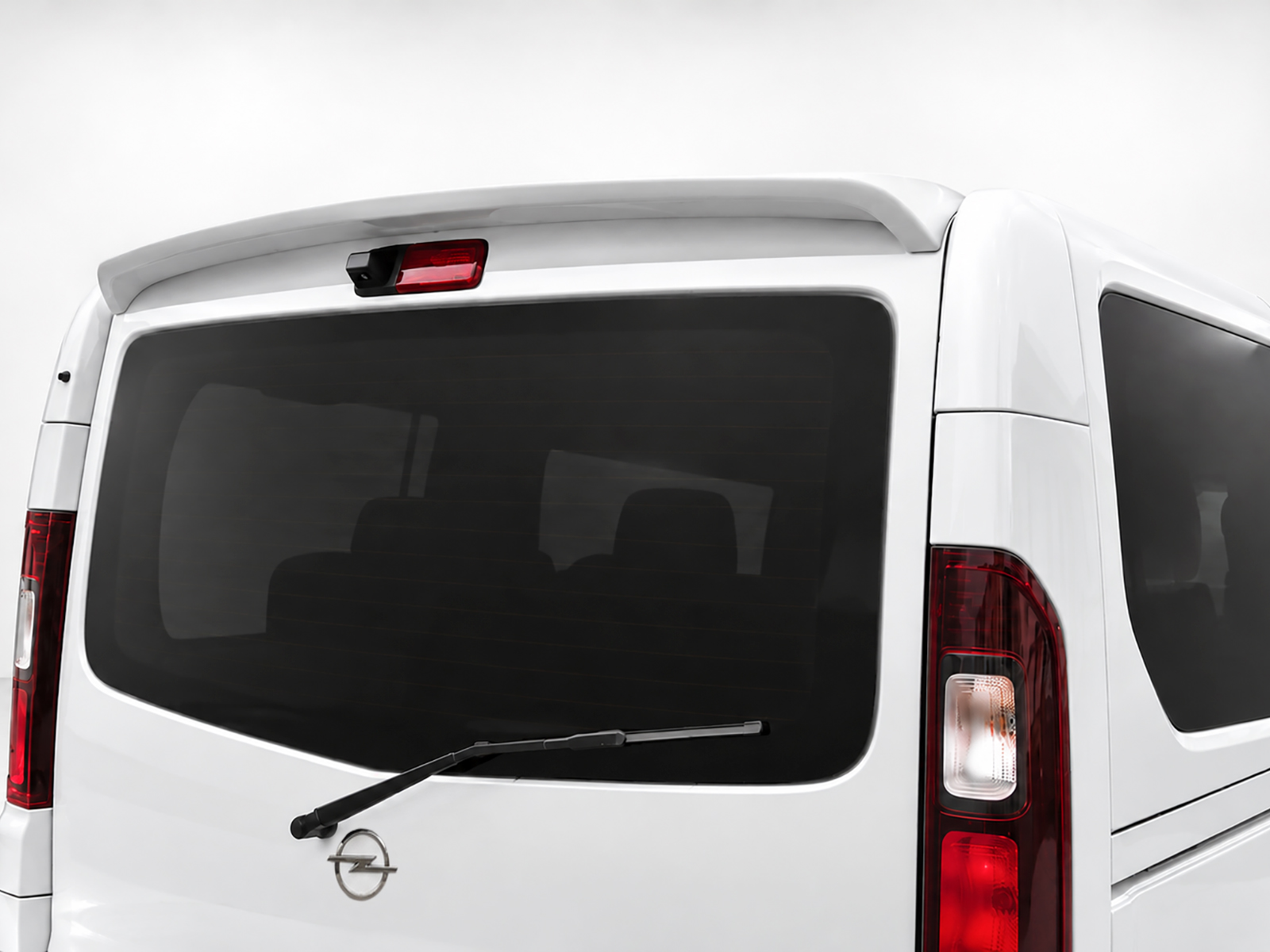 A-455_1jpg - OPSHOLDERS Rear view of a white van with a large tinted back window, rear wiper, and red taillights; Opel badge on the tailgate.