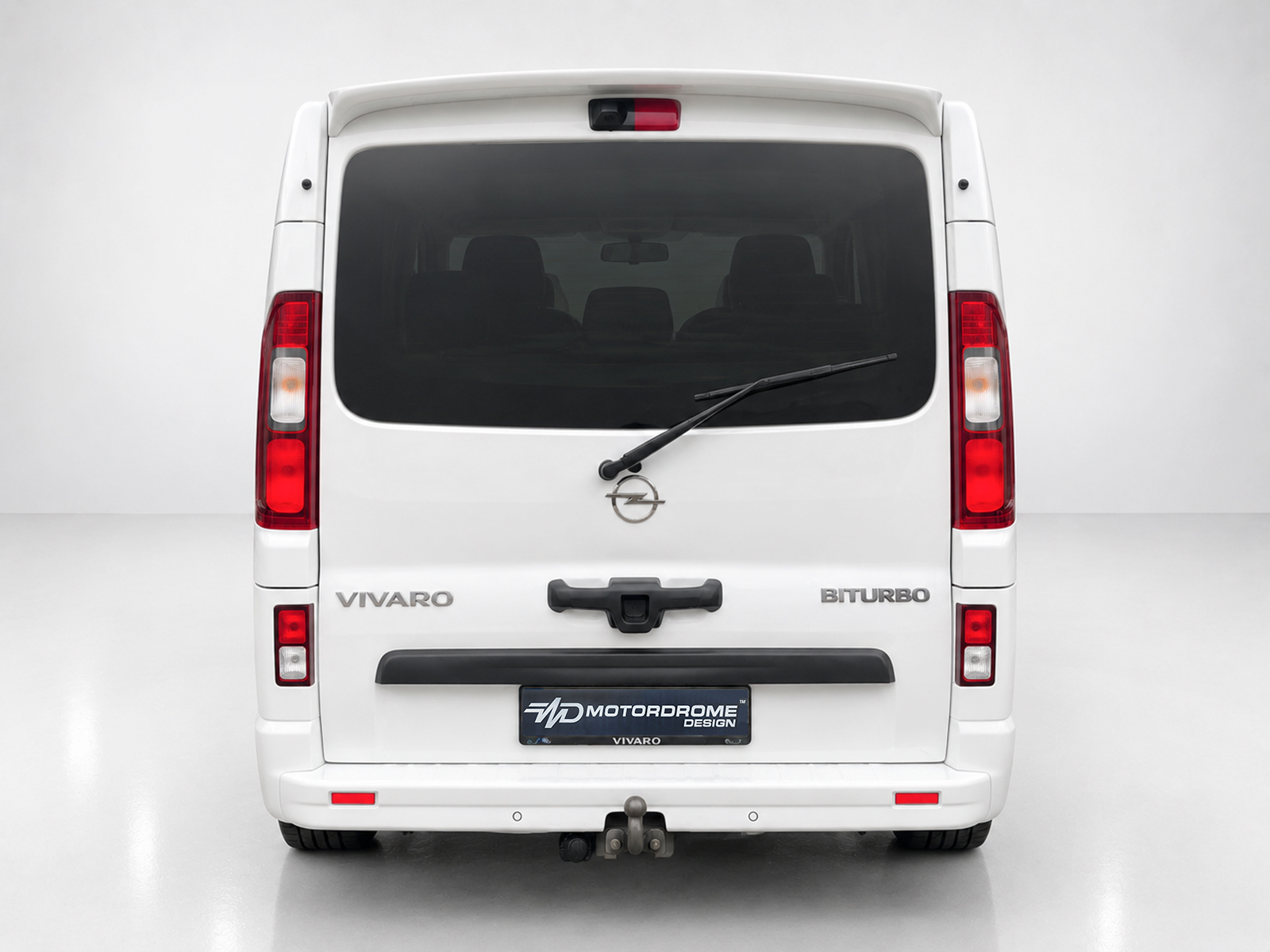 A-455_2jpg - OPSHOLDERS Rear view of a white Opel Vivaro van with 'VIVARO' and 'BITURBO' badges, rear window wiper, and tow hitch