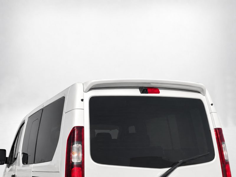 A-455_4jpg - OPSHOLDERS Rear view of a white cargo van showing the large rear window, wiper, and red tail lights in a neutral backdrop.