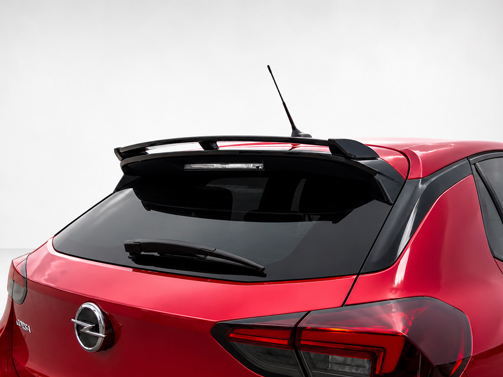 A-456_1jpg - OPSHOLDERS Red hatchback rear end with a spoiler and roof antenna, showing the Opel/Corsa badge on the trunk lid