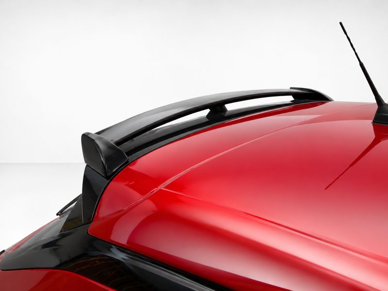 A-456_4jpg - OPSHOLDERS Close-up of a red car roof showing a black rear spoiler and antenna against a light background.