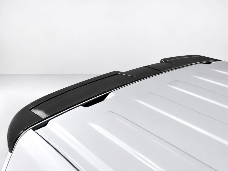 Close-up of a black rear spoiler installed on a white car, highlighting its aerodynamic design along the trunk edge with glossy finishich reflections.