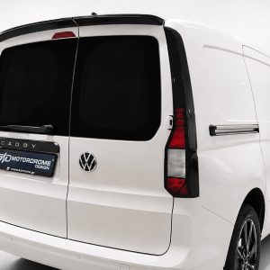 Rear three-quarter view of a white VW Caddy van with black-tinted rear windows and a Motordrome Design license plate.