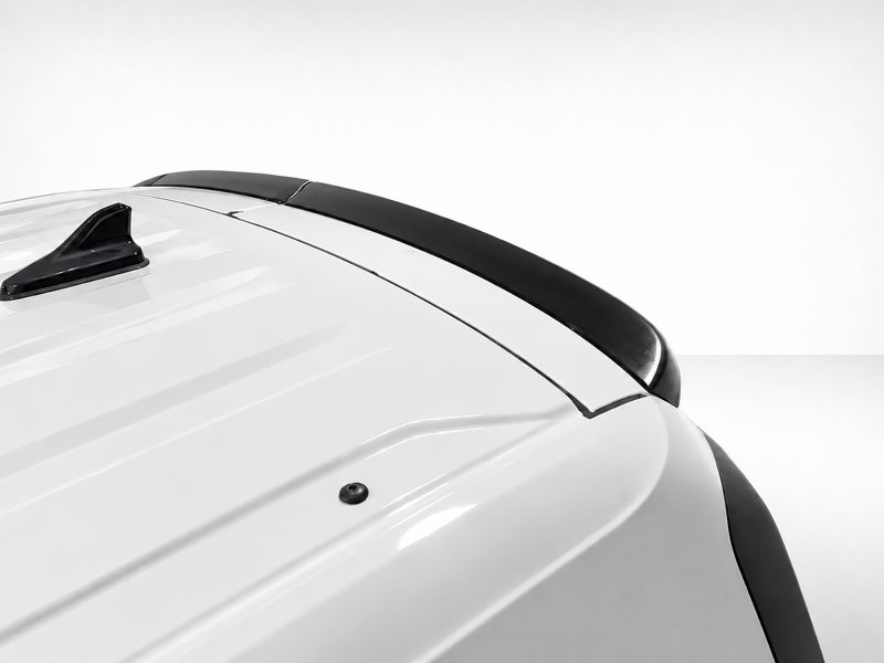 Close-up of a white car roof featuring a black shark-fin antenna and a dark center stripe along the roof.