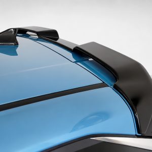 Close-up of a blue car’s rear spoiler and aero edge, highlighting the glossy black wing against a light backdrop.