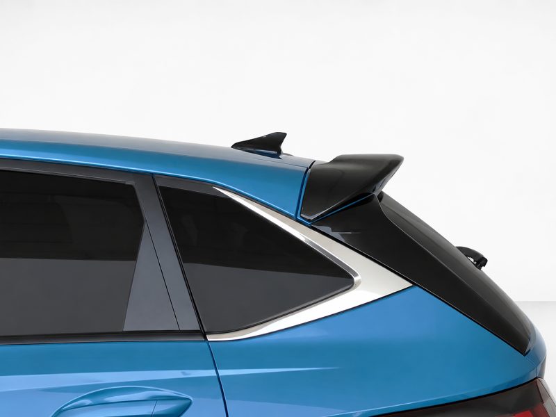 Rear side of a blue car showing a black roof spoiler above the rear window with tinted glass and chrome trim.