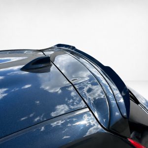 Close-up of a glossy blue car roof with a shark-fin antenna and curved panels reflecting clouds against a light background.