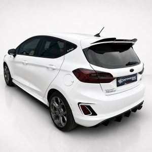 A-476_2jpg - OPSHOLDERS White hatchback/car shown from the rear-left in a bright studio setting, highlighting its spoiler and tinted rear window.
