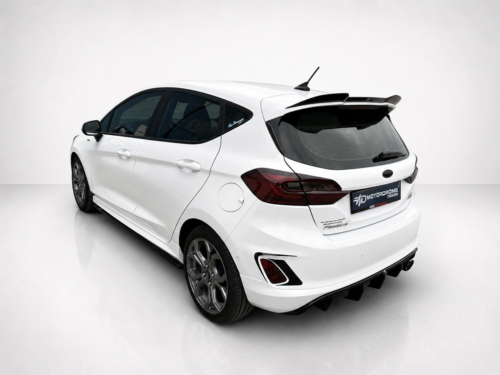 A-476_2jpg - OPSHOLDERS White hatchback/car shown from the rear-left in a bright studio setting, highlighting its spoiler and tinted rear window.
