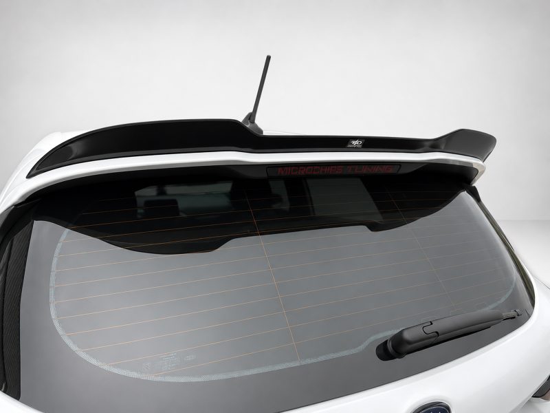 A-476_5jpg - OPSHOLDERS Rear of a white car showing a glossy black spoiler, antenna, and a 'MICROCHIPS TUNING' badge above the rear window with defroster lines visible.