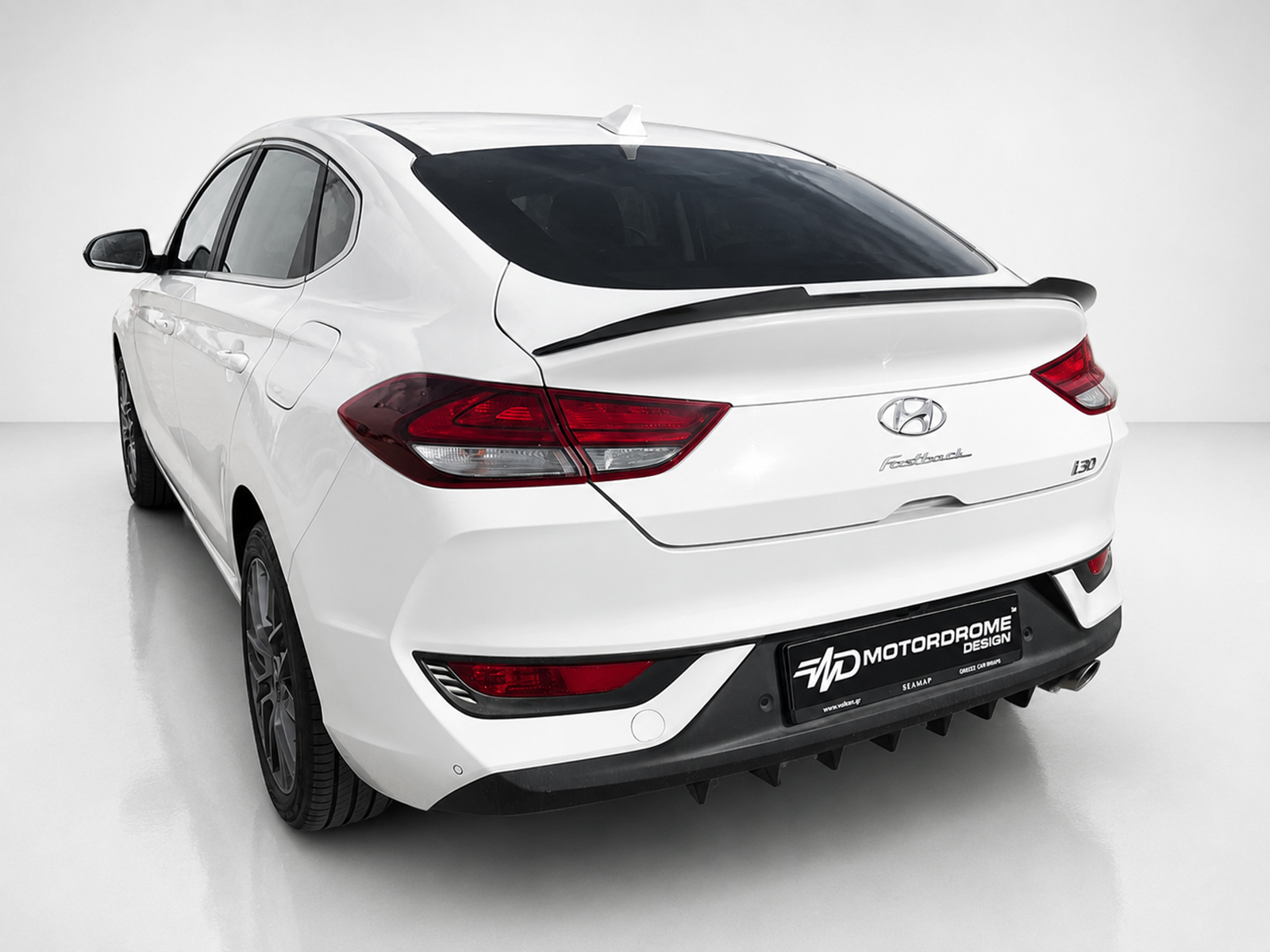 A-477_2jpg - OPSHOLDERS Rear view of a white Hyundai i30 hatchback with a black spoiler in a studio setting