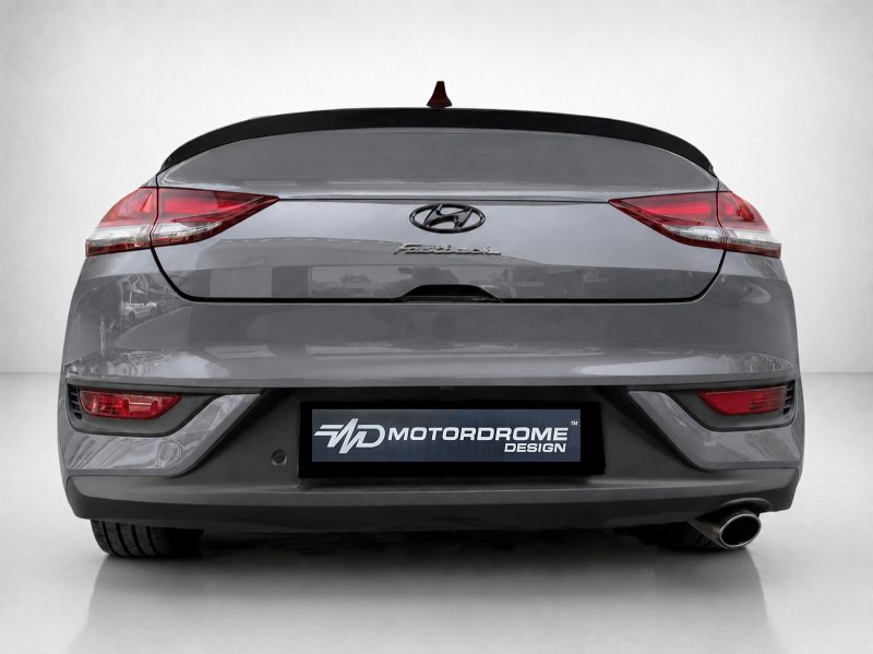 Rear view of a gray Hyundai fastback car with a Motordrome Design license plate plate on the bumper.
