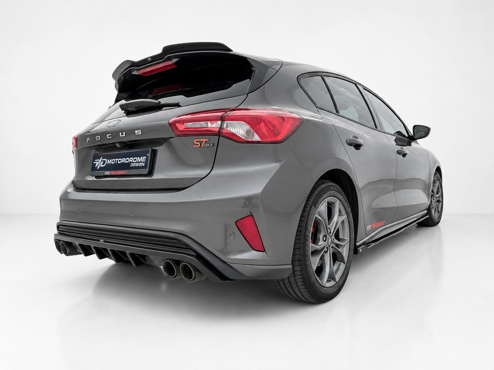 A-479_2jpg - OPSHOLDERS Rear three-quarter view of a gray Ford Focus ST in a studio setting, showing quad exhausts and sporty rear diffuser.