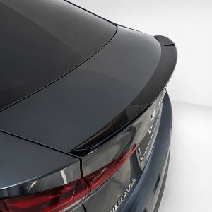 Close-up of the rear end of a dark gray sedan, highlighting the low spoiler and sleek tail lights.