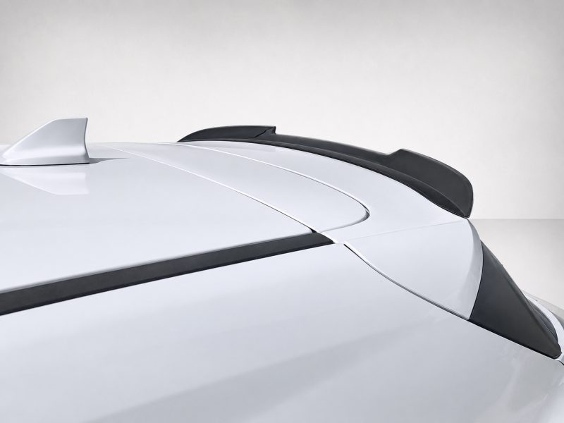 A-481_3jpg - OPSHOLDERS Close-up of a white car roof with a black rear spoiler and sleek body lines against a light background.