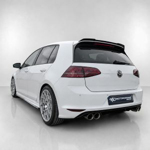 Rear three-quarter view of a white VW hatchback with large alloy wheels and dual exhausts in a studio setting