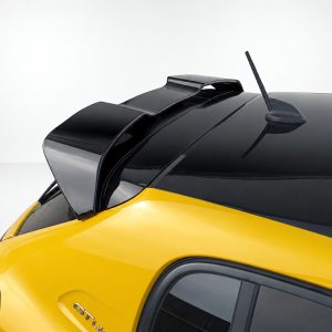 Yellow car with black roof, showing a raised rear spoiler and antenna, viewed from the rear passenger side