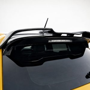 Yellow car seen from above focusing on the black roof spoiler and rear window, with a rooftop antenna visible.