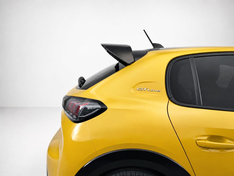 Rear side view of a bright yellow car with a black rear spoiler, GT Line badge, and dark rear window glass against a light background.