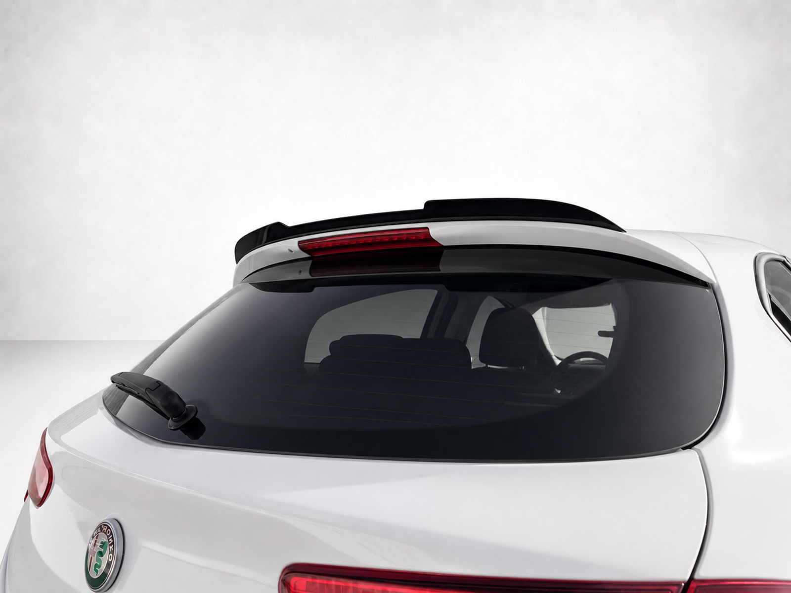 A-485_1jpg - OPSHOLDERS Rear view of a white car showing a rooftop spoiler and rear wiper on the back window, Alfa Romeo badge visible at the lower left.