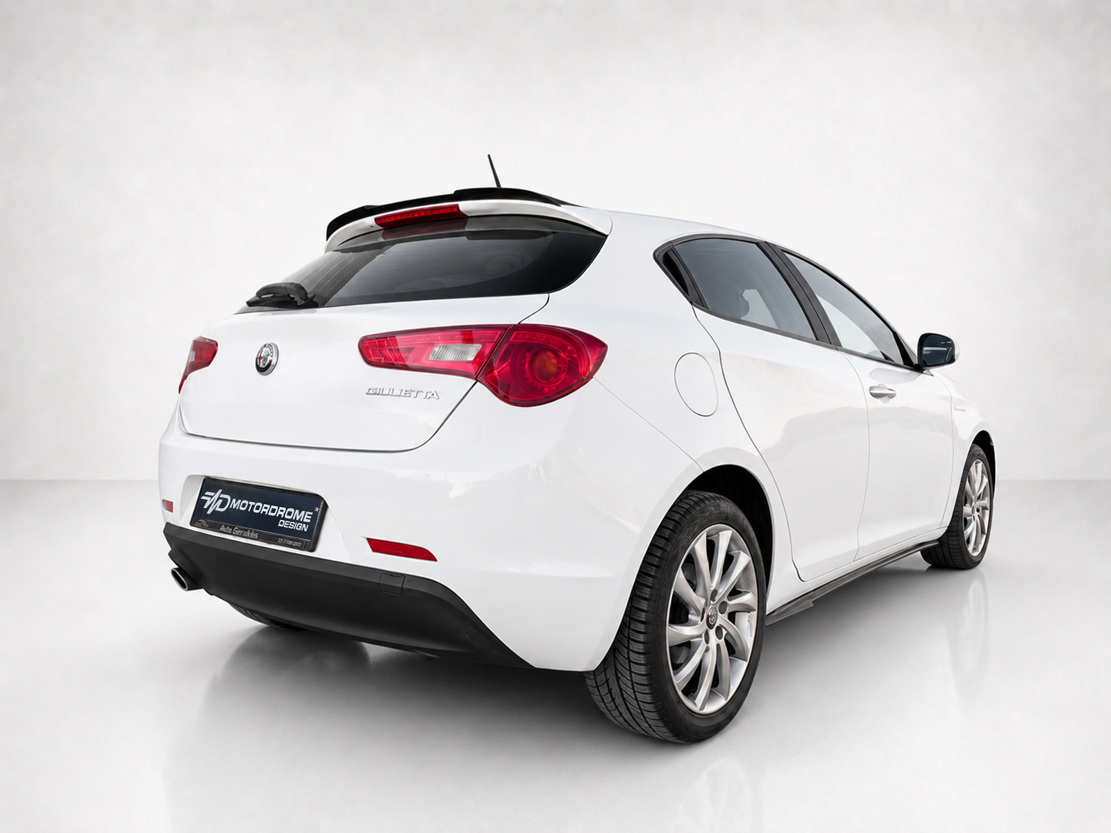 A-485_2jpg - OPSHOLDERS Rear three-quarter view of a white Alfa Romeo Giulietta hatchback in a studio setting with red taillights visible.