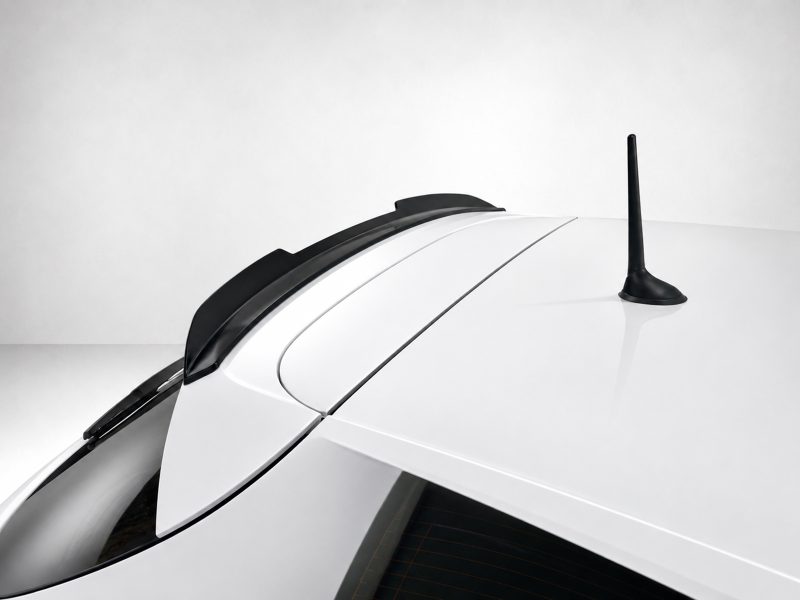 A-485_3jpg - OPSHOLDERS Close-up of a white car roof featuring a black shark-fin antenna and rear window area, viewed from the side.