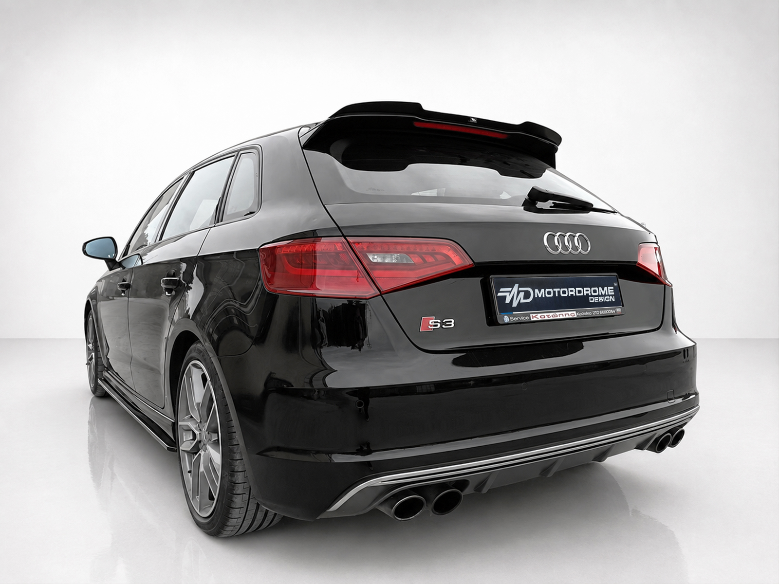 A-487_2jpg - OPSHOLDERS Rear view of a black Audi S3 Sportback in a studio, featuring red taillights, a subtle roof spoiler, and quad exhausts.