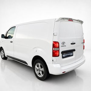 A-488_2jpg - OPSHOLDERS White cargo van shown from a rear-left angle in a studio setting with clean reflective floor. The back doors and taillights are visible.