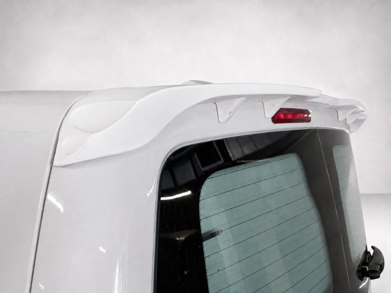 A-488_4jpg - OPSHOLDERS Rear view of a white SUV showing a curved roof spoiler, red brake light, and rear window with defroster lines