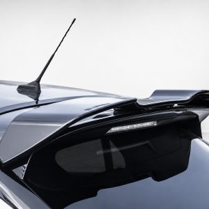 Close-up of a dark metallic car roof showing a rooftop antenna and an integrated rear spoiler over the rear window.