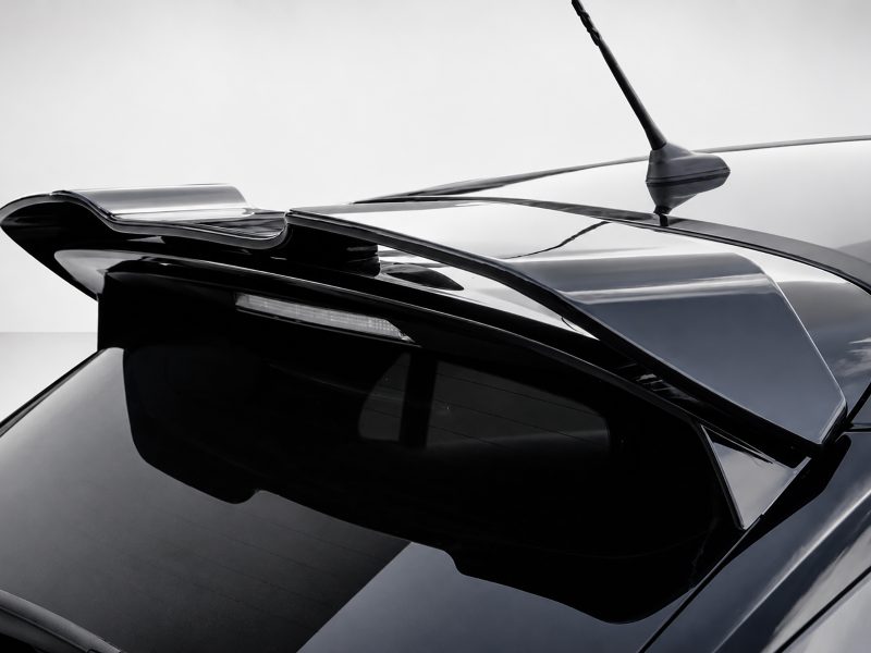 Close-up of a black car rear with a sleek spoiler and antenna against a light background, glossy finish.
