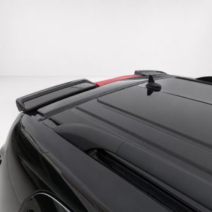 Close-up of a black car roof with a rear spoiler, shark-fin antenna, and red highlight against a light background.