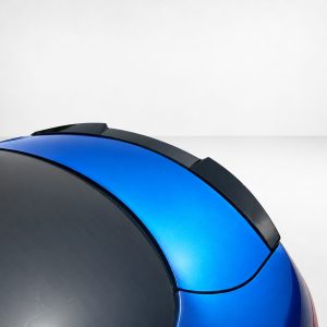 Close-up of a glossy blue and black curved surface against a pale gray background, likely a helmet or vehicle part.