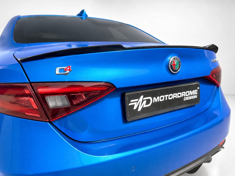 Rear view of a blue car showing the Alfa Romeo badge, a C4 emblem, and a Motordrome Design license plate