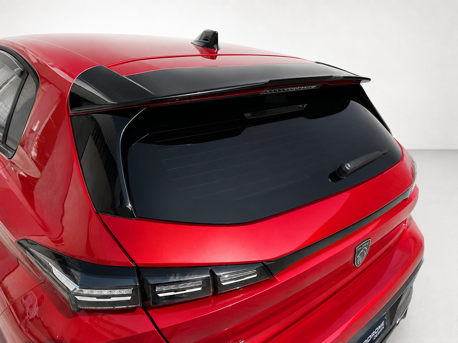 A-492_1jpg - OPSHOLDERS Rear view of a red hatchback/SUV showing a dark rear window, wiper, and a black roof spoiler glaze above the tailgate.