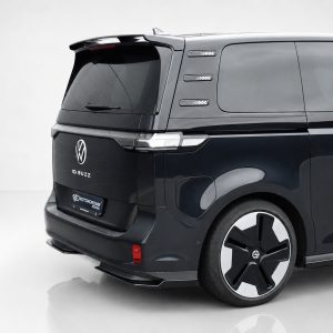Rear-right view of a black VW ID. BUZZ van, showing the back, taillights, and large wheel with a VW emblem on the rim.