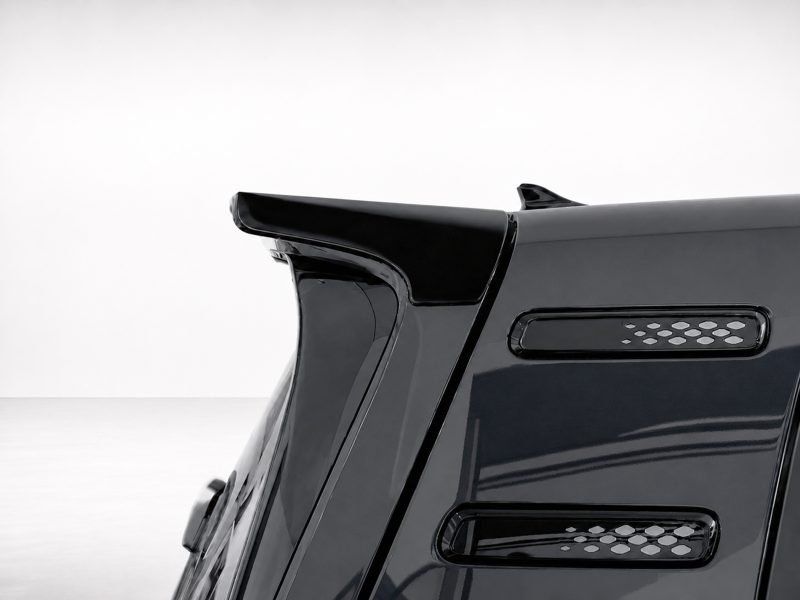 Close-up of a black sports car rear spoiler and vented side panel on a glossy body edge.