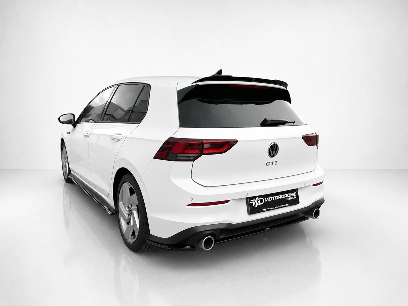A-496_2jpg - OPSHOLDERS White VW Golf GTI wagon photographed from the rear-left side in a studio setting, showing taillights and dual exhausts