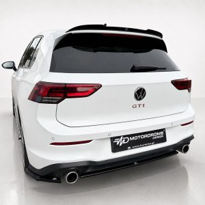 A-496_5jpg - OPSHOLDERS Rear view of a white VW SUV with GTI badge and aftermarket exhaust, in a studio setting with a black rear spoiler and dark taillights.