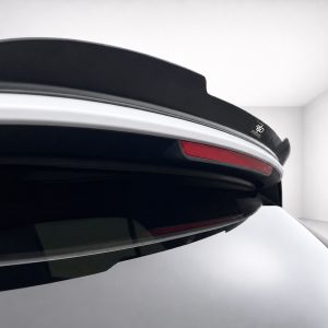 A-496_6jpg - OPSHOLDERS Close-up of a car's rear spoiler with a red taillight strip and black aerodynamic spoiler edge.