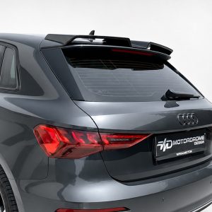 Rear view of a dark gray Audi SUV with a prominent rooftop spoiler and red taillights on a light background.