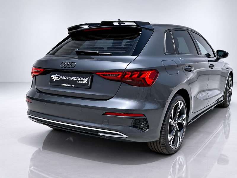 Rear three-quarter view of a metallic gray Audi SUV in a studio, showing taillights, rear hatch, and large alloy wheels with a branded license plate area.