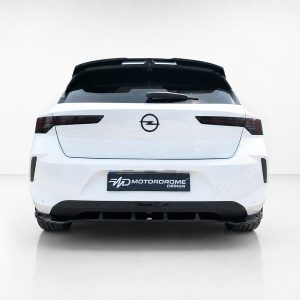 A-501_4jpg - OPSHOLDERS Rear view of a white hatchback with a black roof spoiler, Opel emblem, and a Motordrome Design license plate in a studio setting.