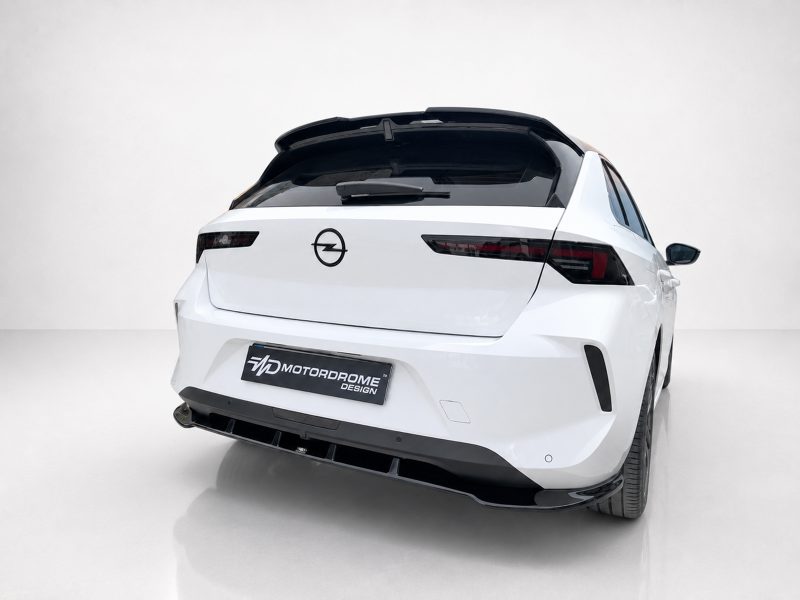 A-501_5jpg - OPSHOLDERS Rear three-quarter view of a white Opel hatchback parked on a showroom floor, featuring a Motordrome Design plate on the bumper.