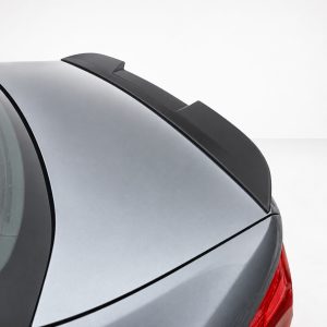 Close-up of a car's rear trunk with a black aerodynamic spoiler on a silver vehicle rear lid, taillight visible at the edge
