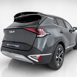 Rear three-quarter view of a dark gray SUV with futuristic styling, visible taillights and a Motorodrome Design badge in a white studio setting.