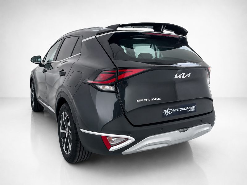 Rear three-quarter view of a dark gray Kia Sportage SUV with red taillights and a roof spoiler in a studio setting