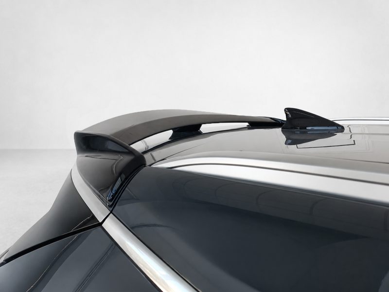 Close-up of a sleek car spoiler on a dark, glossy vehicle with reflections along the trunk edges.